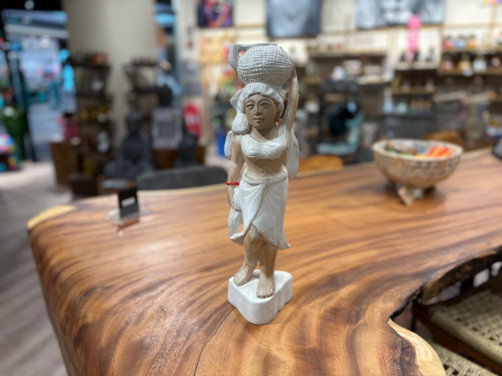 Statue en bois sur table en magasin artisanal.