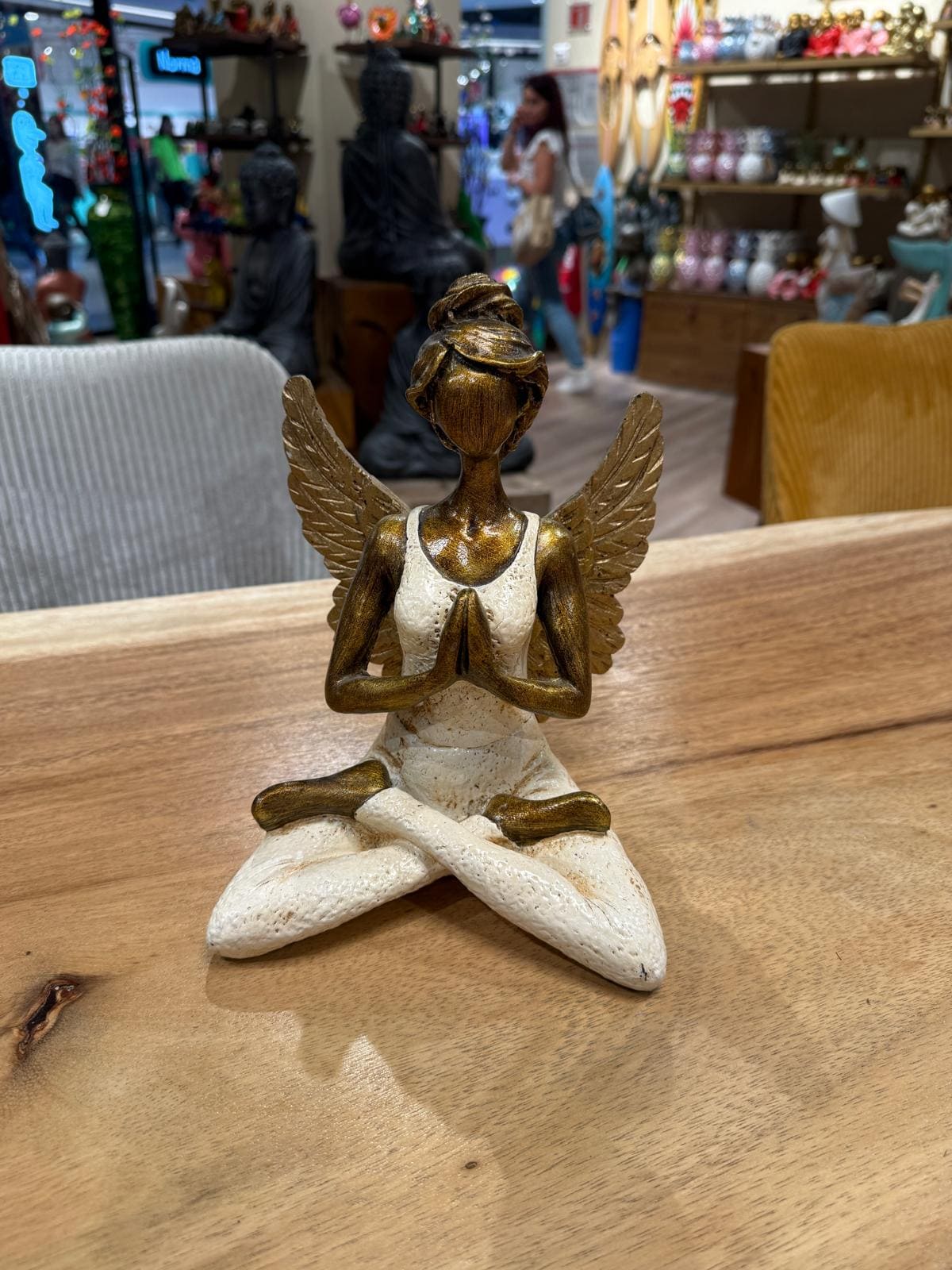 Statue d'ange méditant sur une table en bois.