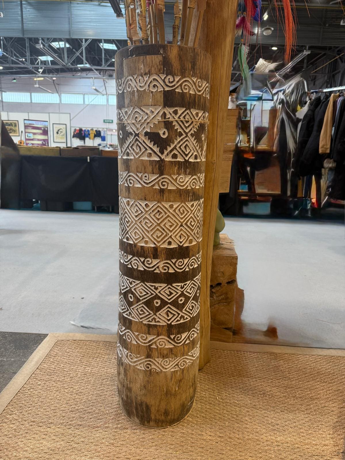 Totem en bois sculpté avec motifs blancs géométriques.
